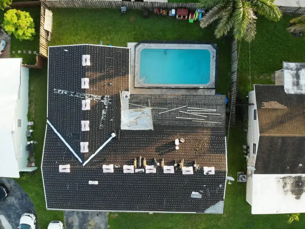 Aerial view of a South Florida re-roof in progress with roofing material staged above the pool deck