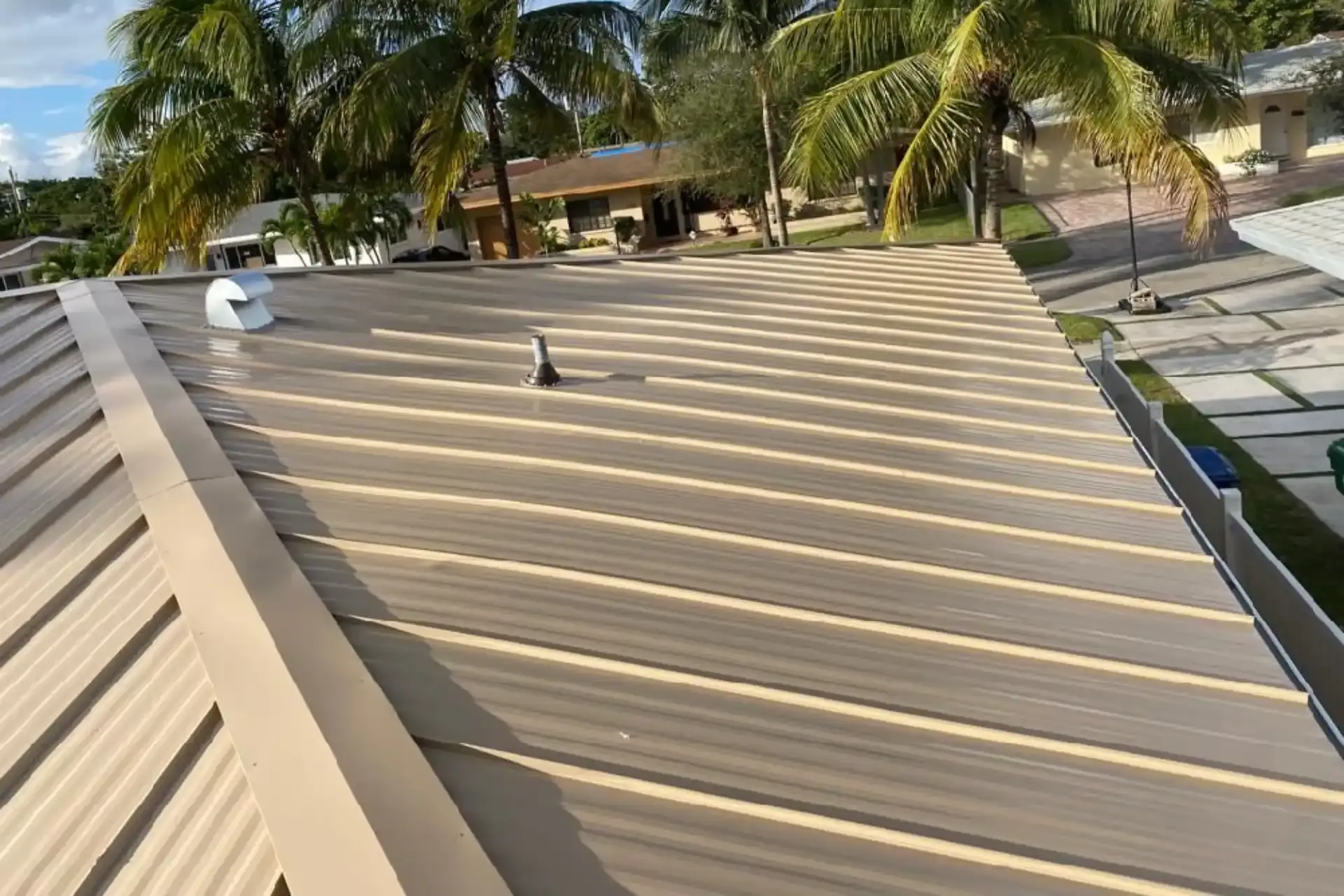 Close-up of a standing seam metal roof on a South Florida home with palm trees behind it
