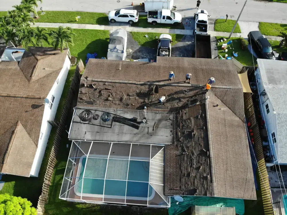 Aerial view of a South Florida home stripped to the roof deck with the crew working around the pool cage